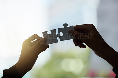 Buy stock photo Cropped shot of two silhouetted hands holding puzzle pieces against a window