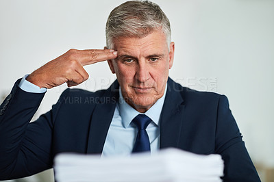 Buy stock photo Shot of a mature businessman looking at paperwork and feeling stressed