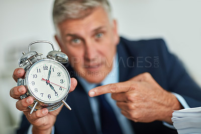 Buy stock photo Portrait of a mature businessman gesturing toward a clock in frustration