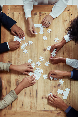 Buy stock photo High angle shot of a group of unrecognisable businesspeople building a puzzle together