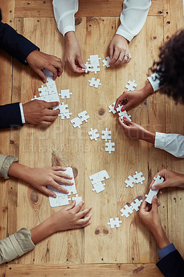 Buy stock photo High angle shot of a group of unrecognisable businesspeople building a puzzle together