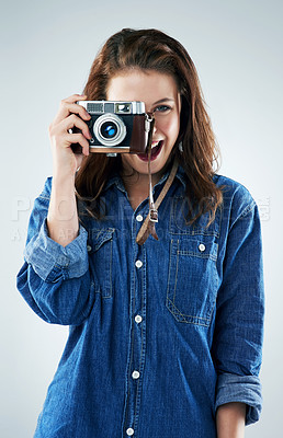Buy stock photo Studio portrait of a young woman using a vintage camera against a grey background