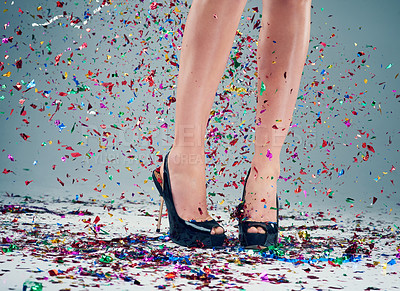 Buy stock photo Studio shot of a young woman's legs in a pair of heels with confetti falling around against a grey background