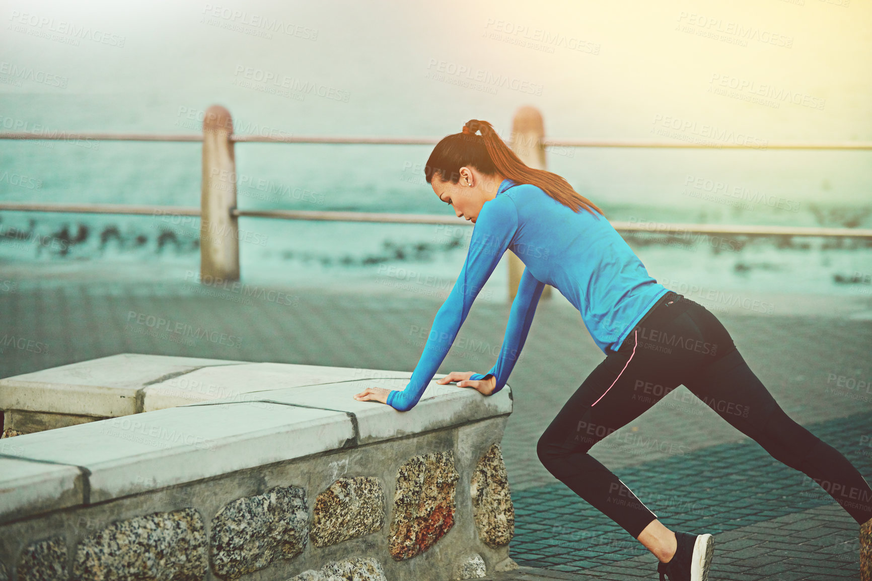 Buy stock photo Shot of a sporty young woman stretching before her run