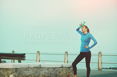 Buy stock photo Shot of a sporty young woman taking a break after her run