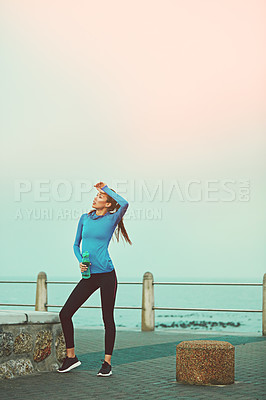 Buy stock photo Shot of a sporty young woman taking a break after her run