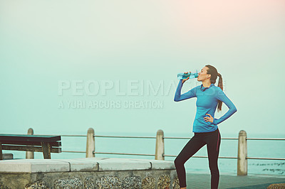 Buy stock photo Shot of a young woman drinking water after her run
