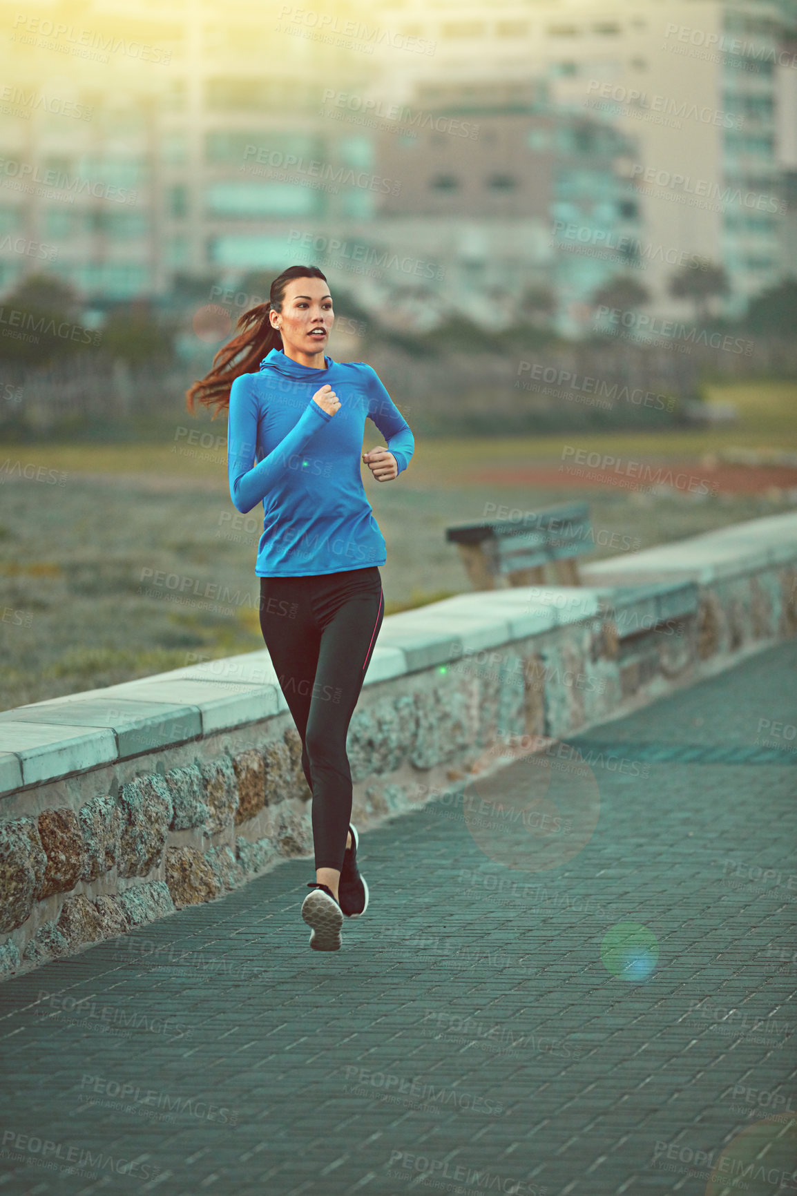 Buy stock photo Shot of a sporty young woman out running on the promenade