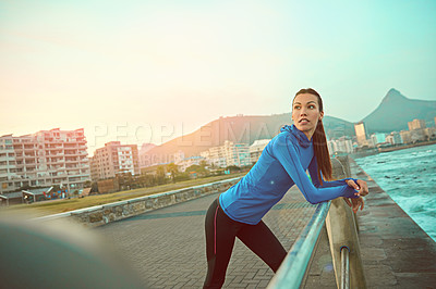 Buy stock photo Shot of a sporty young woman admiring her surroundings after a run