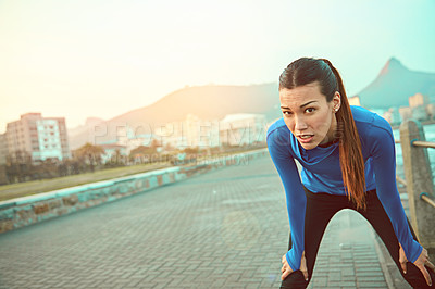 Buy stock photo Shot of a sporty young woman taking a break after her run