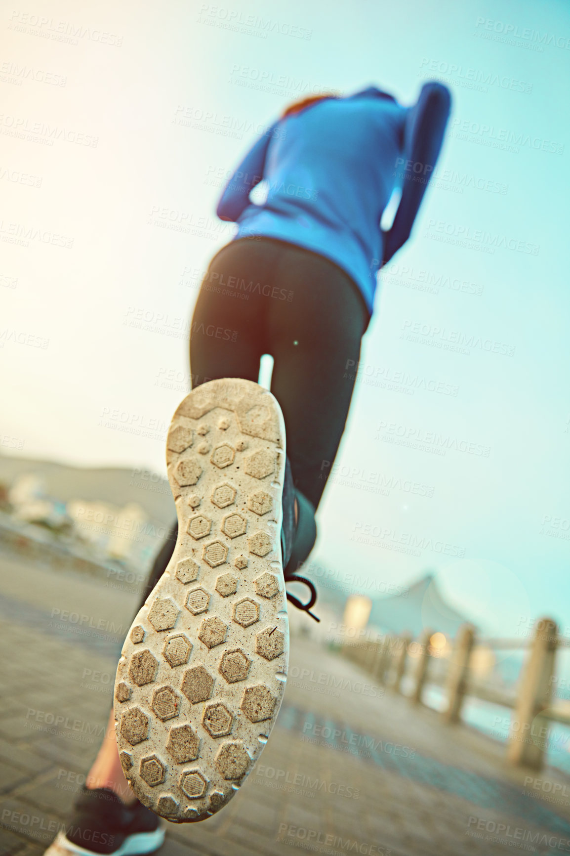 Buy stock photo Shot of a sporty young woman out running on the promenade