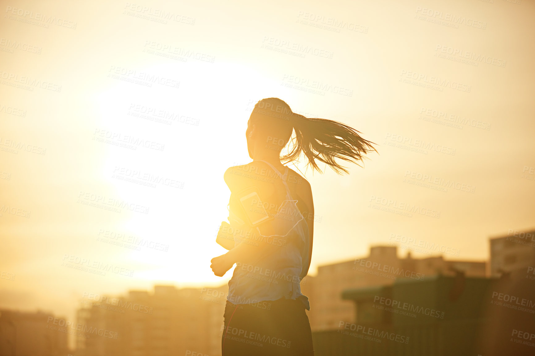 Buy stock photo Shot of a sporty young woman out for a run in the city