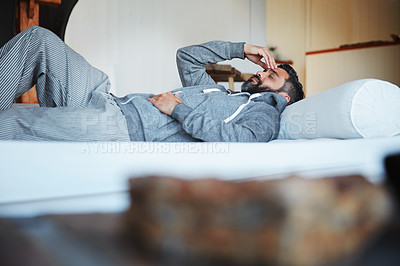 Buy stock photo Tired, sleep and a man with a headache on a bed with burnout, looking sad and depressed. Fatigue, insomnia and a person with depression, anxiety or a migraine problem in the bedroom of a house