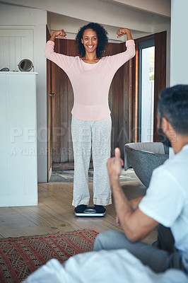 Buy stock photo Shot of a mature woman weighing herself on a scale while her husband watches