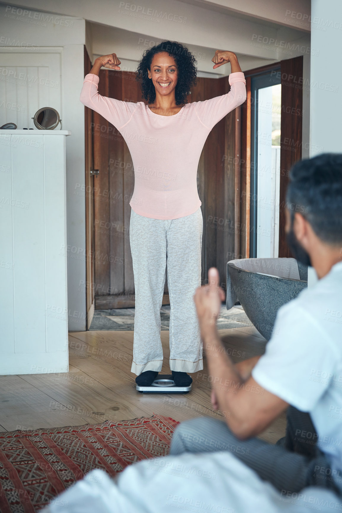 Buy stock photo Shot of a mature woman weighing herself on a scale while her husband watches