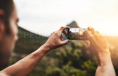 Buy stock photo Cropped shot of a man taking a picture of the scenery at the top of a mountain