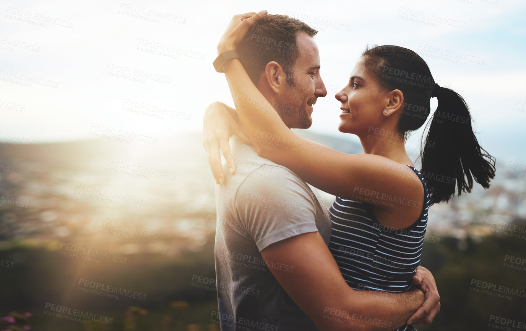 Buy stock photo Shot of a young couple in a loving embrace outdoors