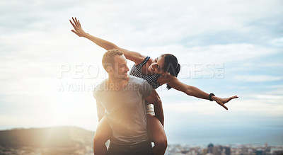 Buy stock photo Shot of a happy young couple enjoying a piggyback ride outdoors