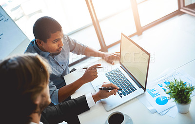 Buy stock photo High angle shot of two young colleagues using a laptop together in the office