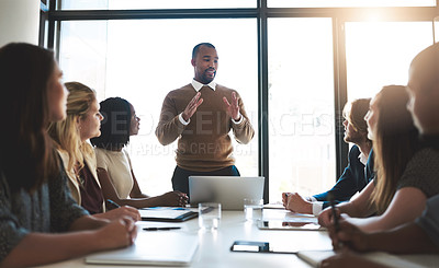 Buy stock photo Shot of a young businessman leading his team in a meeting in the office