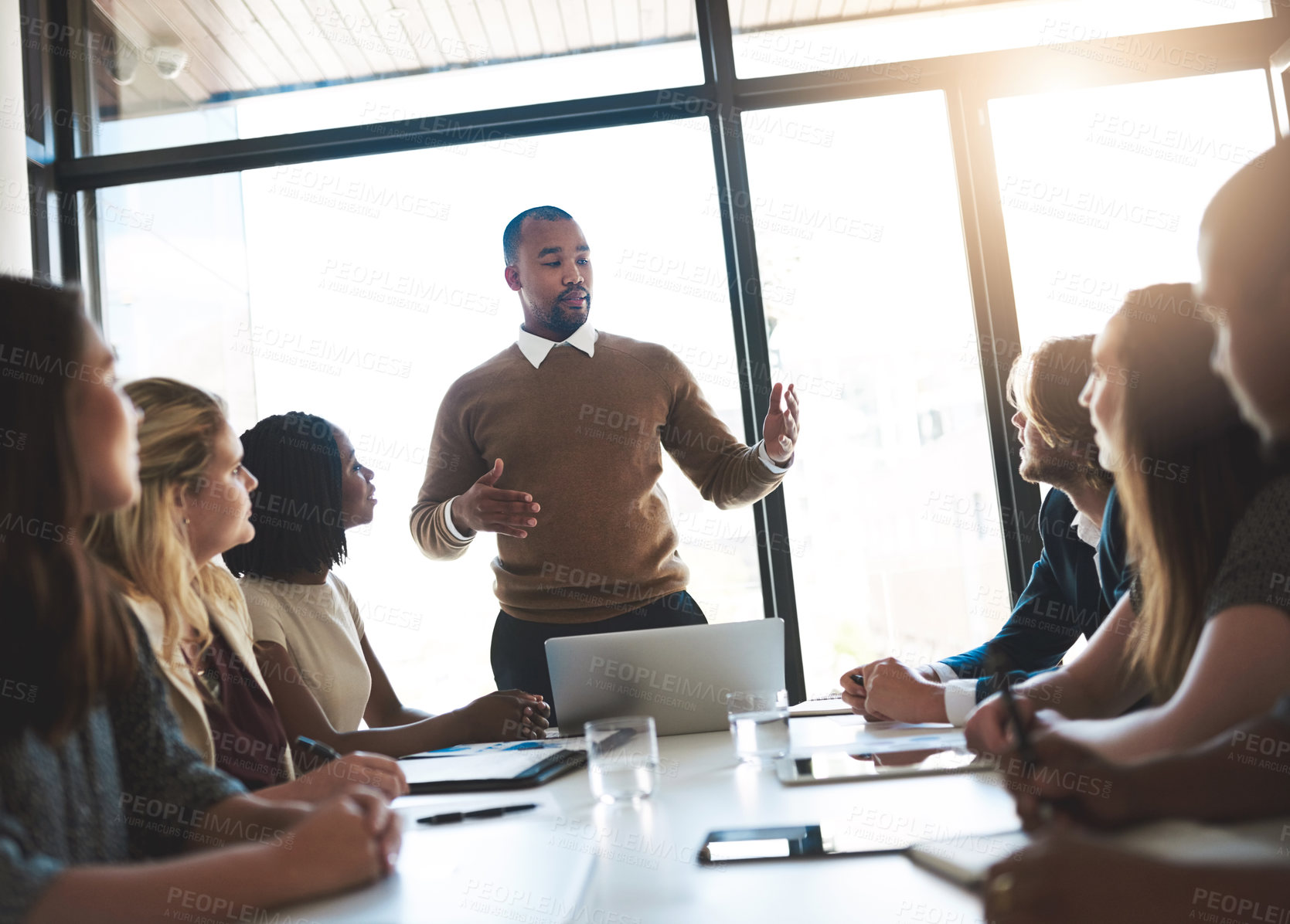 Buy stock photo Shot of a young businessman leading his team in a meeting in the office