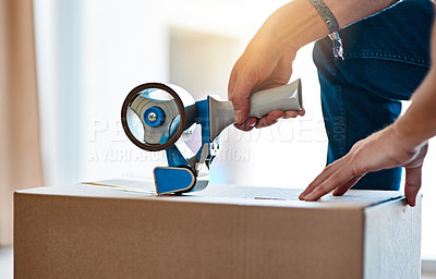 Buy stock photo Shot of an unrecognizable young man closing a cardboard box with tape at home