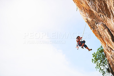 Buy stock photo Shot of a young rock climber scaling a cliff face