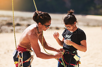 Buy stock photo Shot of two rock climbers adjusting their harnesses