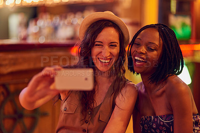 Buy stock photo Cropped shot of two young friends taking a selfie in a bar