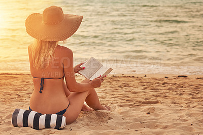 Buy stock photo Rearview shot of an unidentifiable woman in a bikini reading on a tropical beach