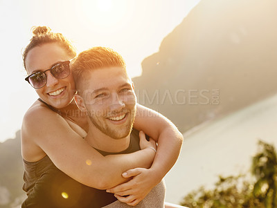 Buy stock photo Portrait of a young man giving his girlfriend a piggyback ride outside