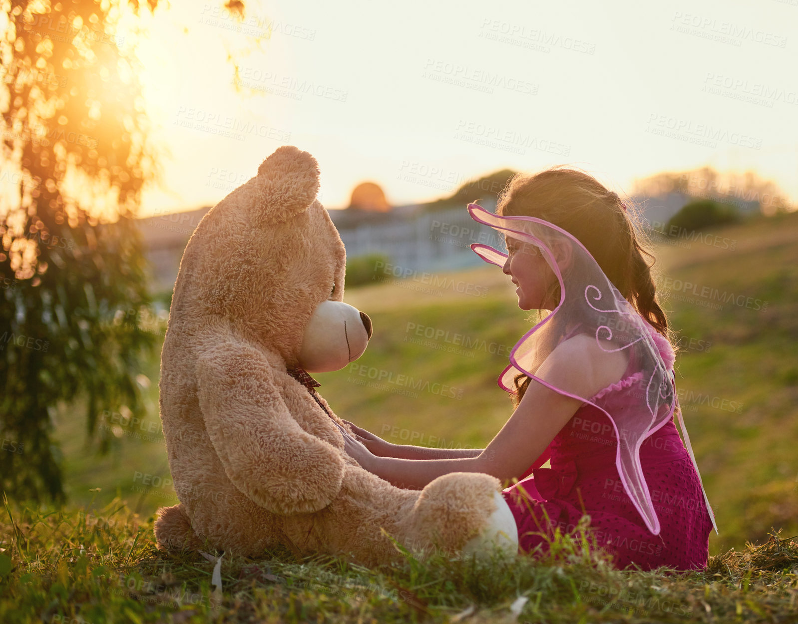 Buy stock photo Shot of a cute little girl playing with a huge teddybear in the park