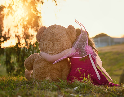 Buy stock photo Rearview shot of a cute little girl playing with a huge teddybear in the park