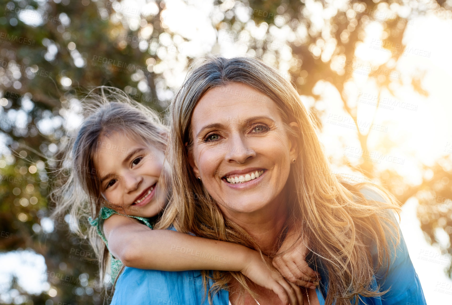 Buy stock photo Love, portrait or mother and daughter with piggyback hug in a park for fun, adventure and journey outdoor at sunset. Happy family, face and mom carrying girl in a forest with support, trust or games