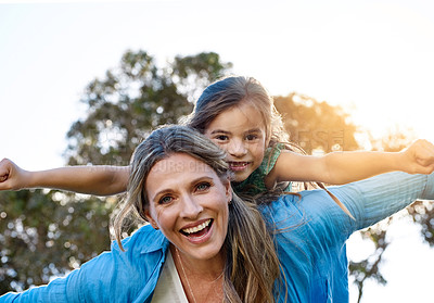 Buy stock photo Portrait of a happy mother and daughter enjoying a piggyback ride outdoors