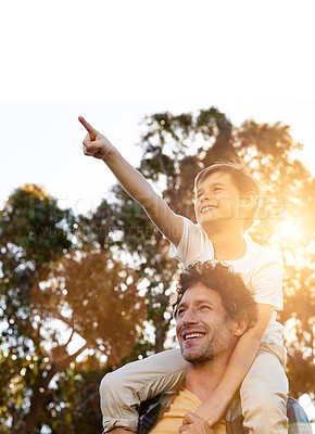 Buy stock photo Shot of a happy boy pointing at something while being carried by his father outdoors