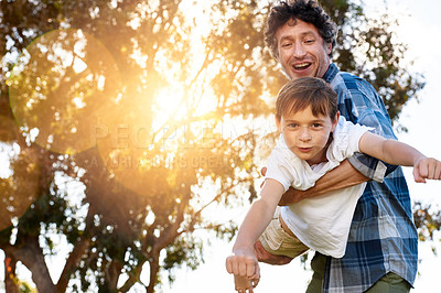 Buy stock photo Portrait of a happy father playfully carrying his son during a fun day outdoors