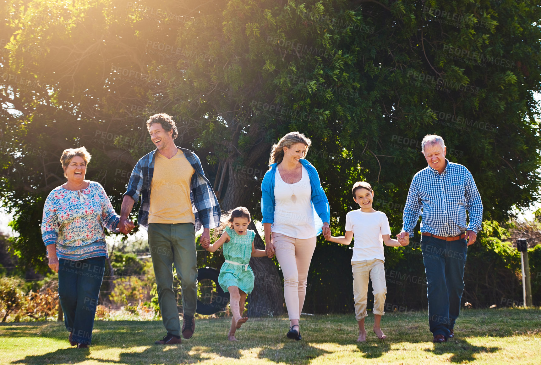 Buy stock photo Shot of three generations of family walking hand in hand outdoors