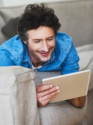 Buy stock photo Shot of a bachelor relaxing on the sofa with his tablet