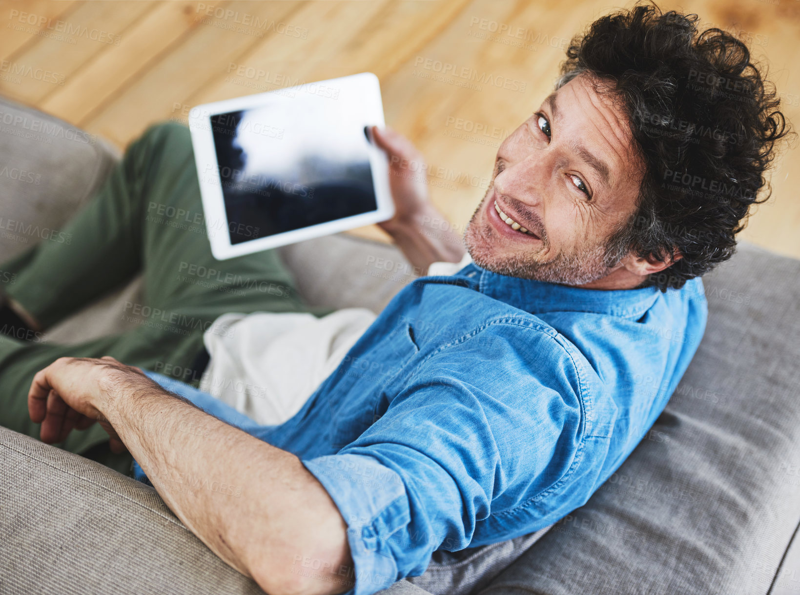 Buy stock photo Top view, portrait and man with tablet on couch for relax, online and streaming movies in living room. Happy, technology and internet for games, social media and connection or communication in home