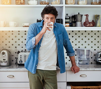 Buy stock photo Shot of a bachelor enjoying a cup of coffee while relaxing in his kitchen at home