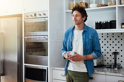 Buy stock photo Shot of a bachelor lost in contemplation while drinking a cup of coffee in his kitchen