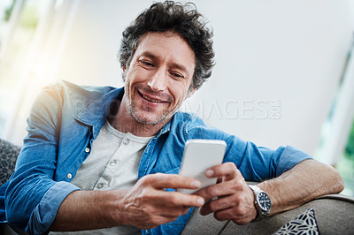 Buy stock photo Shot of a bachelor relaxing on the sofa with his smartphone