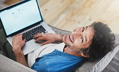 Buy stock photo High angle portrait of a happy bachelor relaxing on the sofa with his laptop