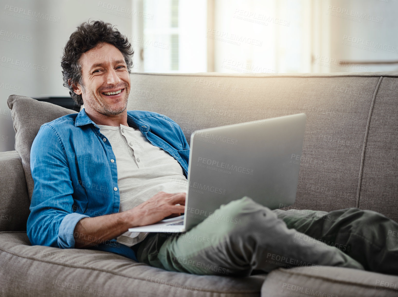 Buy stock photo Portrait, happy man and laptop on couch for relax, online and streaming movies in living room. Male person, technology and internet for games, social media and smile for reading email in home