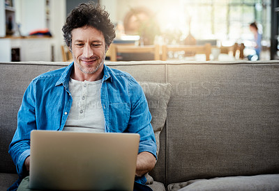 Buy stock photo Shot of a happy bachelor relaxing on the sofa with his laptop