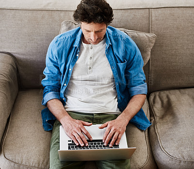 Buy stock photo High angle shot of a happy bachelor relaxing on the sofa with his laptop