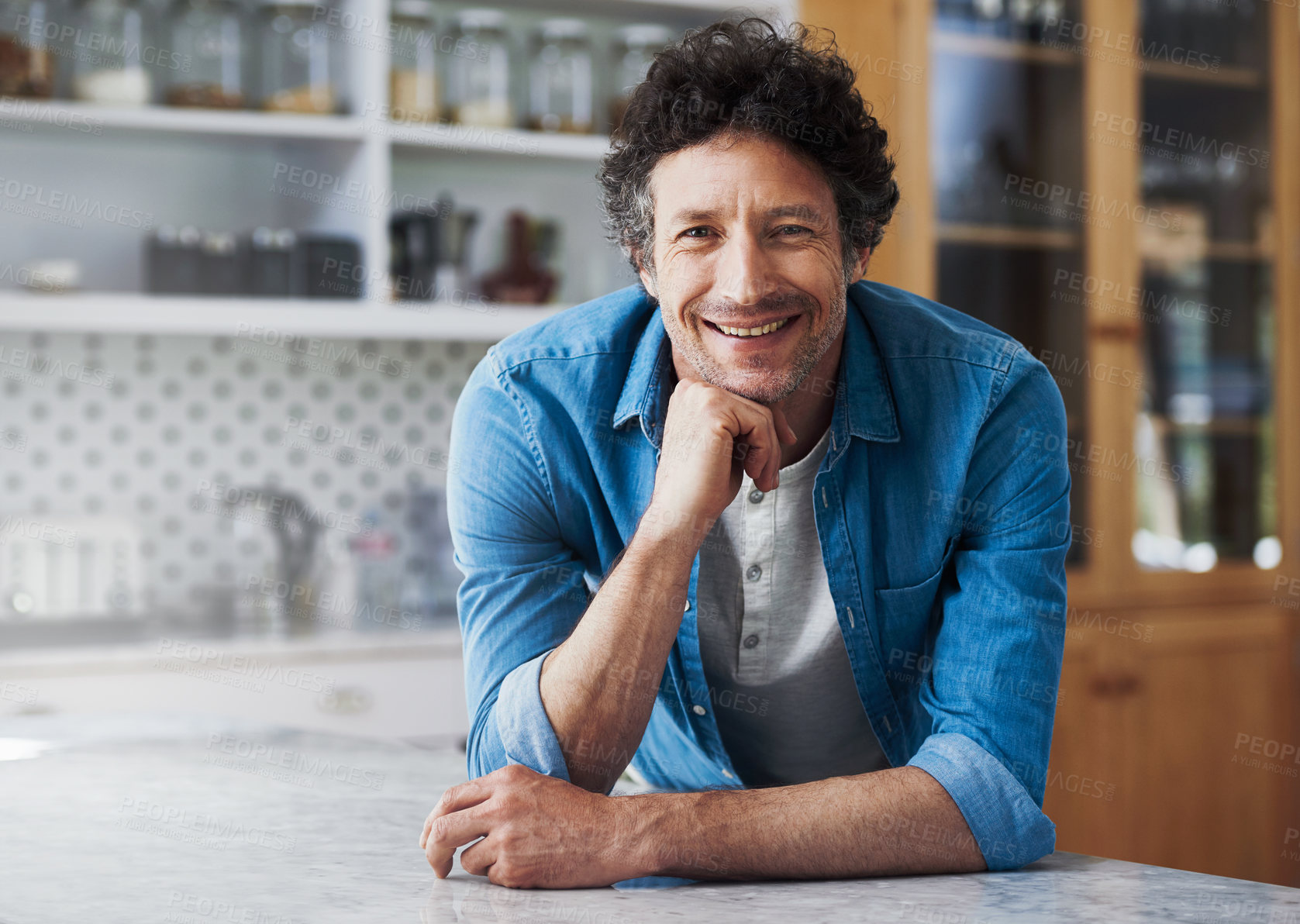 Buy stock photo Portrait of a happy bachelor leaning on his kitchen counter