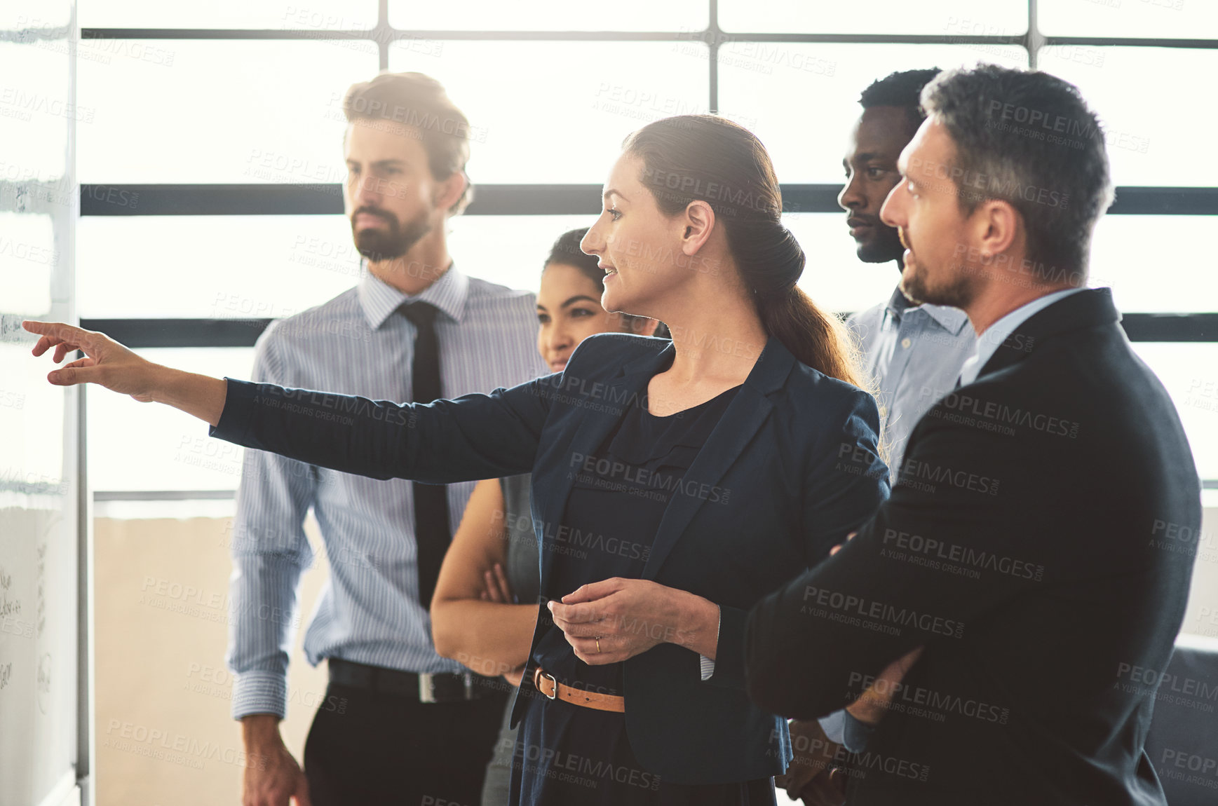 Buy stock photo Shot of young businesspeople discussing ideas on a whiteboard during a meeting in an office