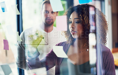 Buy stock photo Cropped shot of a group of young designers brainstorming with notes on a glass wall in an office